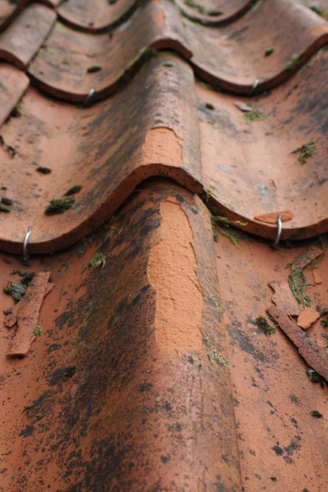 Närbild på Vittinge enkupigt E13-tegel på tak med sprickor och mossa som visar åldring och slitage.