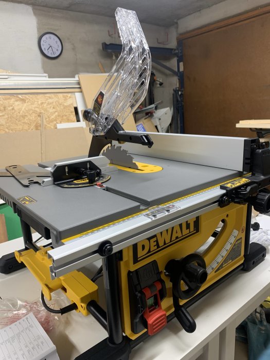 Ny Dewalt bordsåg uppackad i verkstad, med skyddsplast och klocka på väggen i bakgrunden.