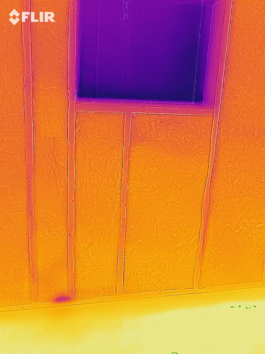 Termografibild som visar isolering i en vägg med små kyl-läckor vid glipor och reglar.