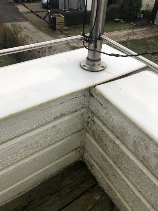 Vit plast som täcker balkongvägg där skarvar inte är täta, med ett rostfritt räcke skruvat ovanpå.
