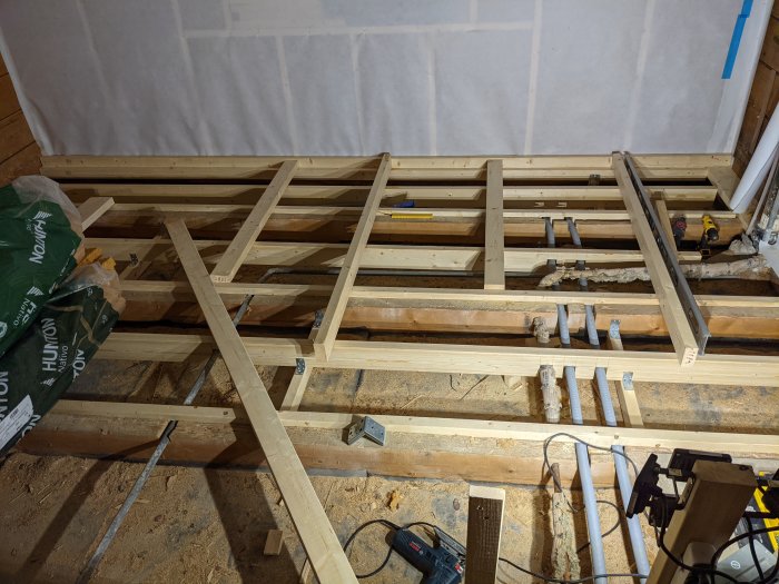 Bjälklag under konstruktion med tillagd 45x120mm träregel, verktyg och byggmaterial synligt.