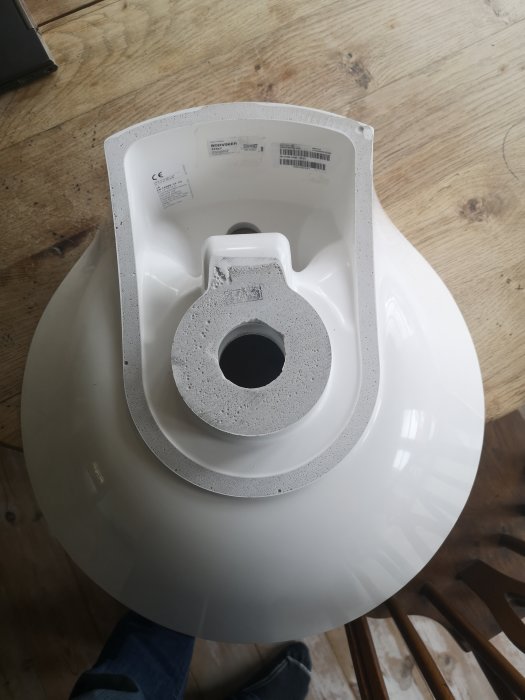 Översiktsbild av ett vitt, cirkulärt handfat sett uppifrån med synligt avlopp och utskjutande del under blandarområdet.
