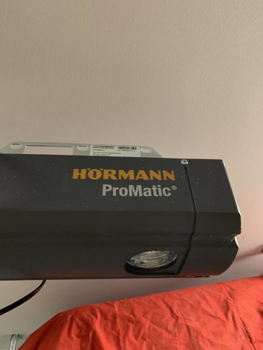 Hörmann ProMatic garageportsmotor monterad på en vägg ovanför en röd duk.