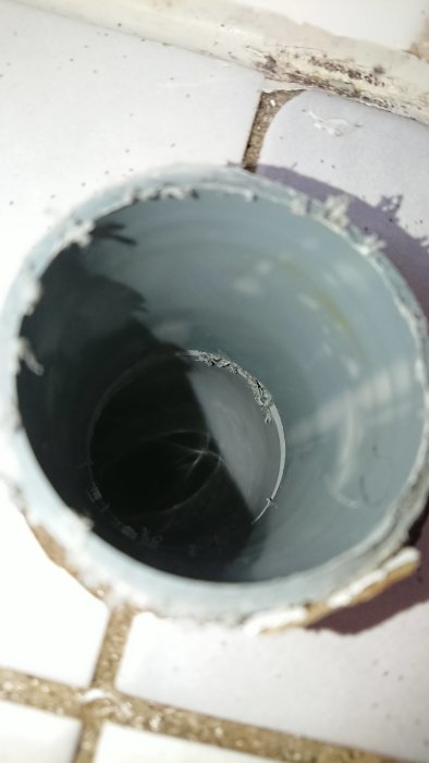 Nött avloppsrör i golv med synlig skada där ett gamla golvrör tidigare mött röret.