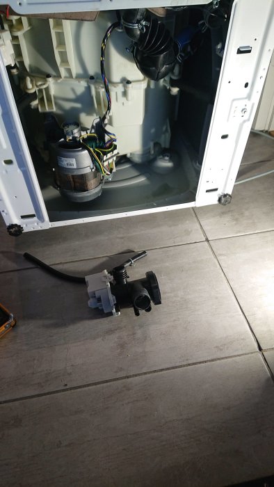 Öppen diskmaskin med demonterad pump på golvet, verktyg synligt, reparation utförd.