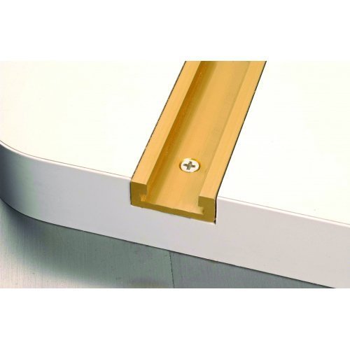 Guldfärgad T-spårsskena fastskruvad i kanten på ett vitt arbetsbord för verktygsprecision och modifikation.