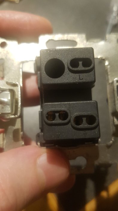 Hand håller en eluttag dubbelanslutning utan frontplatta.