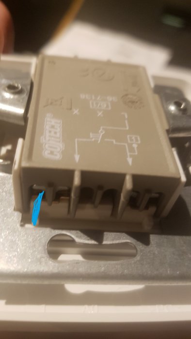 Elektrisk komponent monterad på skena med schema på ovansidan, fokus på komponenten, suddig bakgrund.