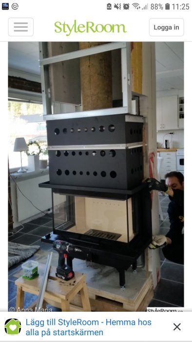 Installationsprocess av svart köksfläkt med runda ventileringshål, person som arbetar nära fläkten.