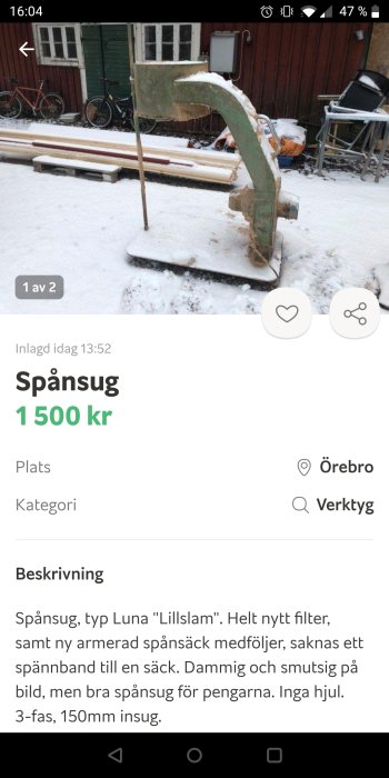 Spånsug av typ Luna "Lillslam" står i snö framför en röd byggnad med cyklar i bakgrunden.