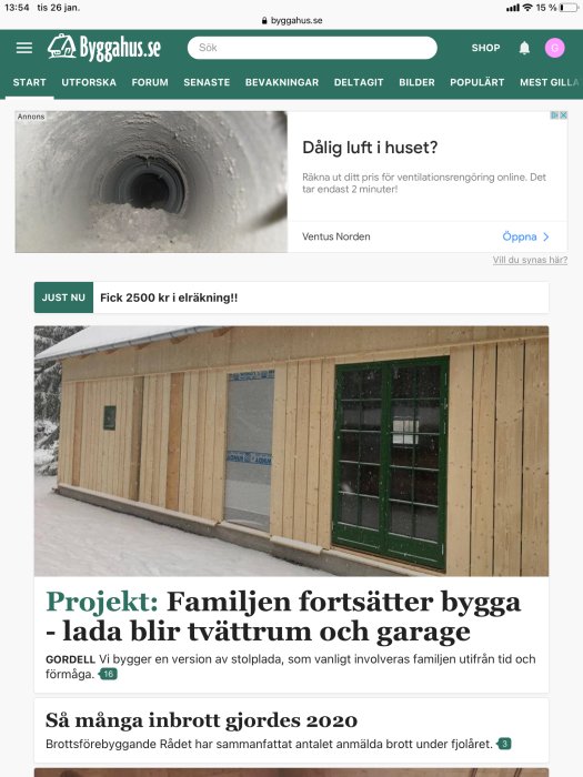 Delvis färdigställd byggnad med OSB-skivor på väggarna och ett grönt fönster, snö på marken.