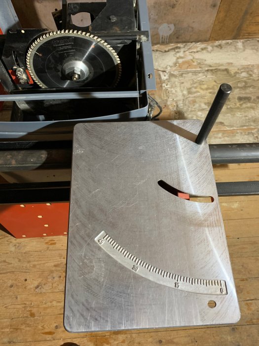 Aluminiumbord för justerbart sågbord med sågblad och uppmärkta graderingsgränser.