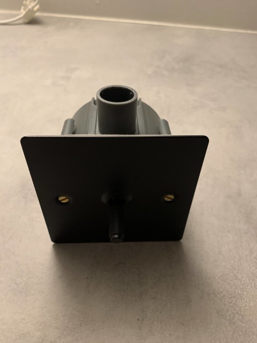 Elskåp med svart frontplatta, rotationsknapp och röranslutning mot en grå bänkskiva.