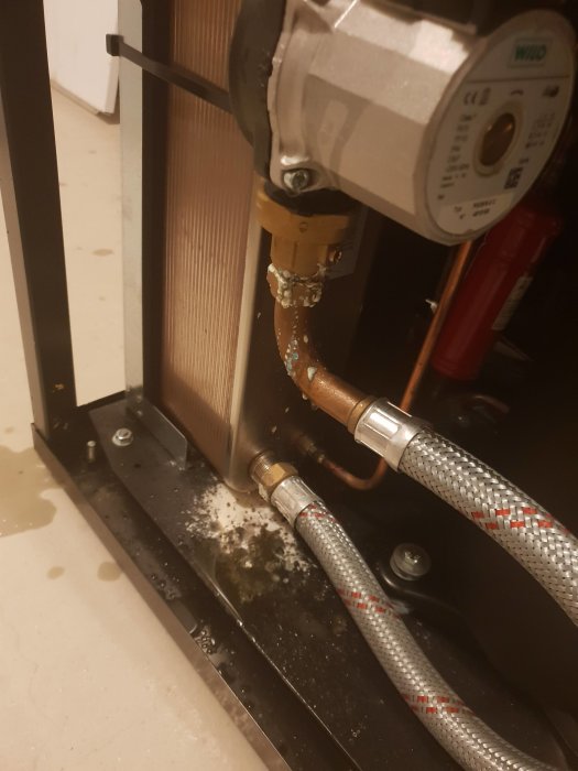 Värmepump med vita avlagringar och misstänkt läckage vid anslutningarna.