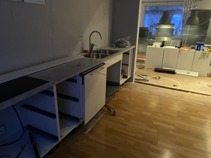 Pågående köksrenovering med omonterade skåpluckor och verktyg utspridda på golvet.