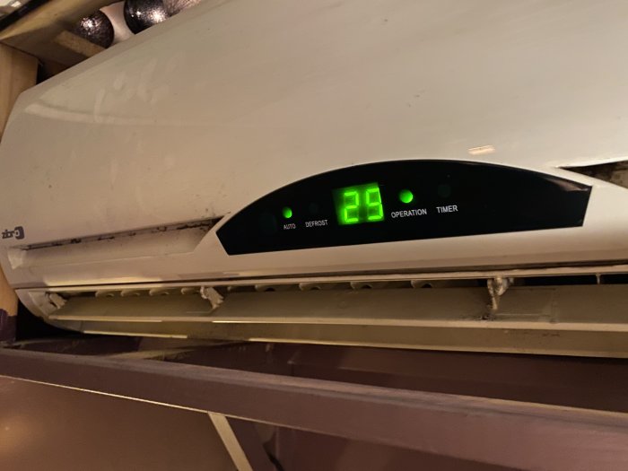 En äldre Zibro luftvärmepump med digital display som visar 26 grader, synliga tecken på slitage och smuts.