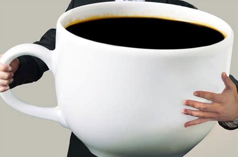 Person som håller i en överdimensionerad kaffekopp fylld med kaffe.