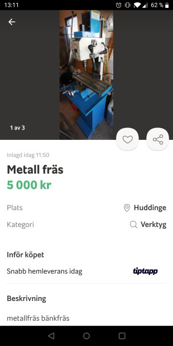 Vertikal metallfräs på en blå arbetsbänk, omgiven av verktyg och lådor i en verkstad.