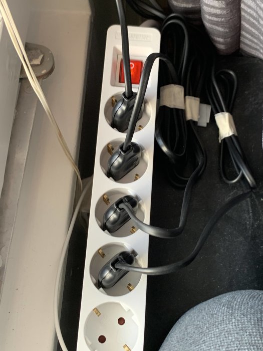 Grenuttag kopplat till en plugg in dimmer i vägguttag med fyra lampsladdar inkopplade och dimmerknapp på.