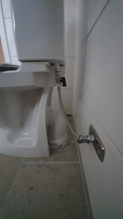 Toalettstol från IFÖ installerad med synligt avloppsrör och utrymme mellan vägg och cistern.