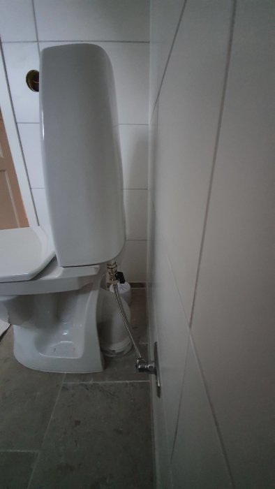 Toalettstol med synligt avloppsrör som sticker ut längre från väggen p.g.a. smal cistern, inte dolt som förväntat.