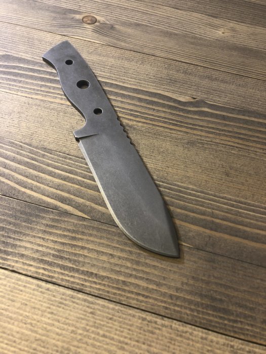 Obehandlad kniv av 90MnCrV8 stål med ej färdigställt handtag på träbakgrund.