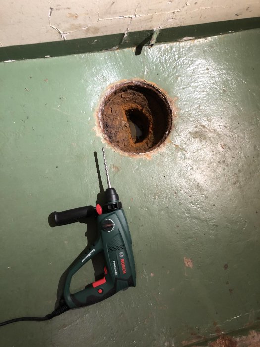 Rostig golvbrunn i betonggolv med en Borsch borr bredvid, diskussion om bytning och avlägsning.