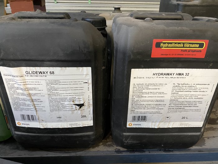 Två dunkar med industrioljor, GLIDEWAY 68 och HYDRAWAY HMA 32, på en hylla.