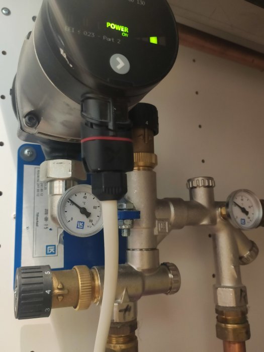 Värmepumpsinstallation med Nibe F730 och anslutna rör, termostatinställning och manometer som visar temperatur och tryck.