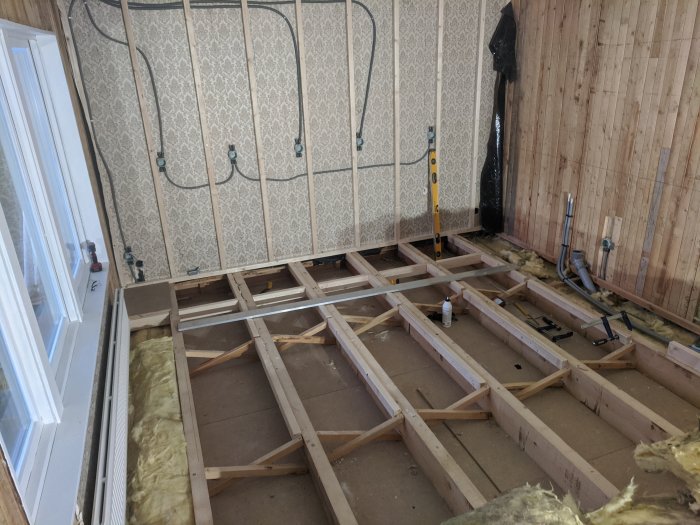 Uppskruvade reglar monterade på deformera bjälkar i ett pågående renoveringsprojekt för ett kök.