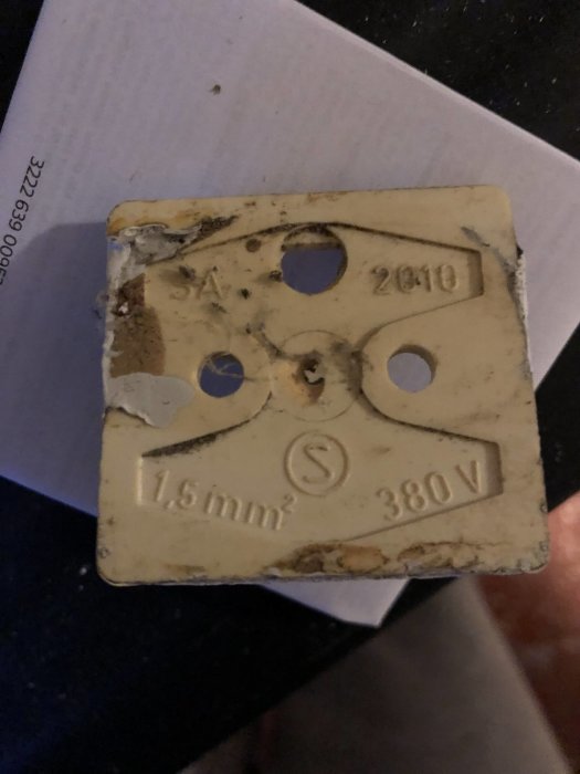 Smutsig och slitna etikett med texten "2010 1,5mm² 380V" möjligen från en elektrisk dosa.