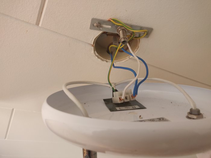 Öppen taklampa med synliga kablar och WAGO-kopplingar som illustrerar en diskussion om ovanlig jordning i sovrum.