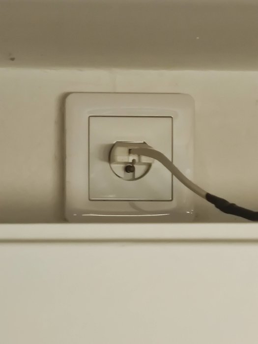 Kabel ansluten till ett vägguttag ovanför ett skåp i ett kök.