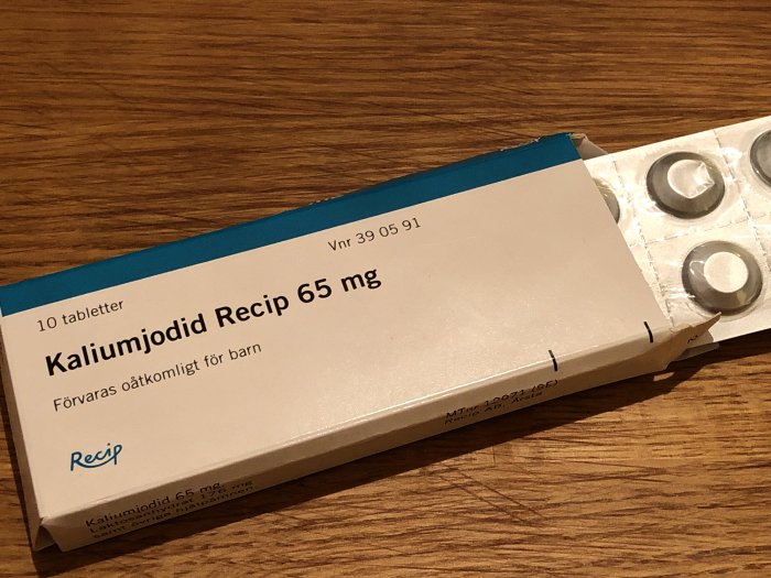Förpackning av Kaliumjodid Recip 65 mg tabletter, delvis öppnad på ett träbord.