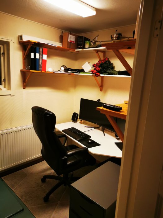 Ett pannrum omvandlat till minikontor med skrivbord, stol och hyllor före renovering.