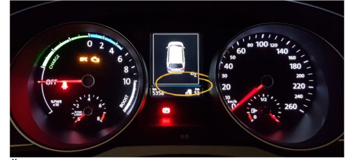 Bilens instrumentbräda med varvräknare, hastighetsmätare och en central display som visar en laddningsindikator.