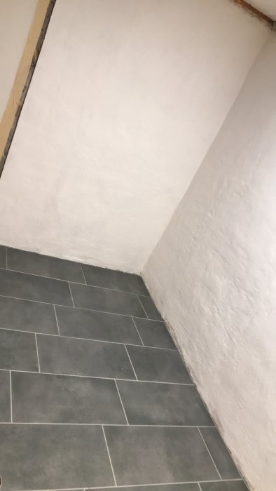 Renoverat hörn med nytt mörkt klinkergolv och vitmålade väggar.