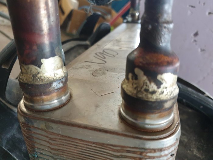 Närbild på två svetsade metalldelar med synliga svetssömmar och oxidering.