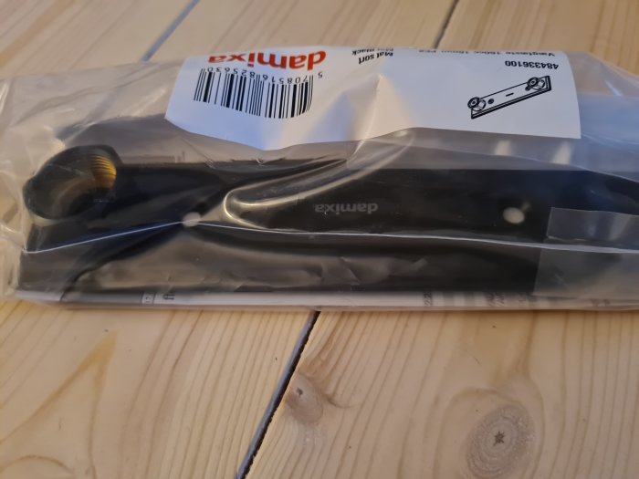 Mattsvart blandarfäste Damixa i förpackning på träbord.