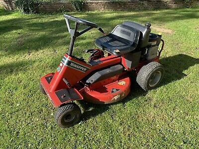 Röd och svart Murray Snapper åkgräsklippare parkerad på en gräsmatta.