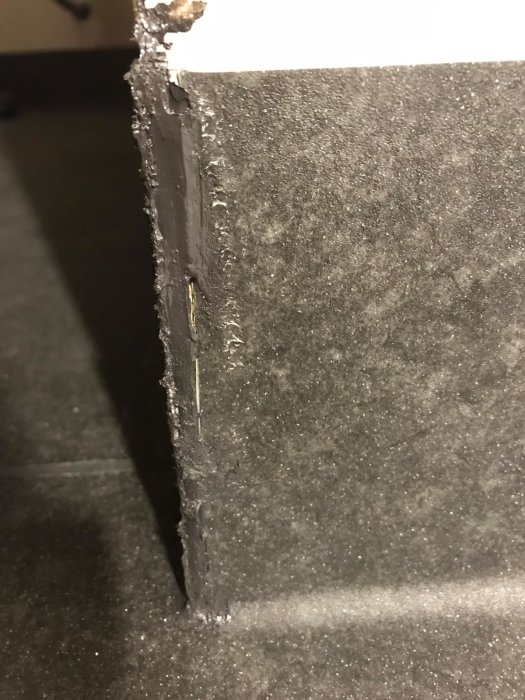 Ojämn och ruggig skarv på en nyinstallerad våtrumsmatta i hörnet av ett rum, vilket ger ett otillfredsställande utseende.