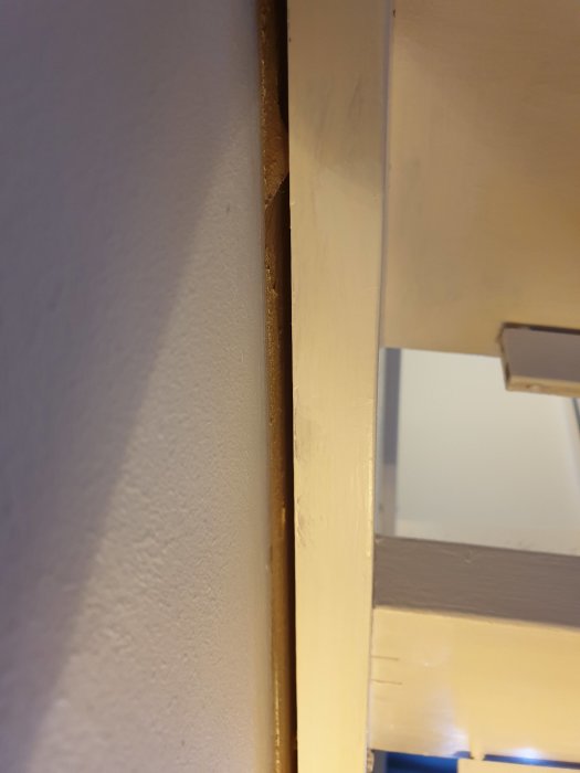 Glipa mellan vangstycke av trätrappa och betongvägg, tecken på möjlig rörelse eller lösa fästelement.