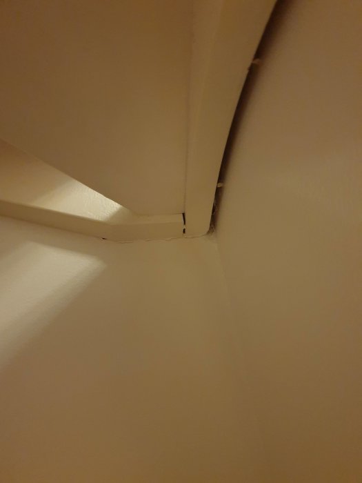 Vitt vangstycke som sticker ut och är fogat från väggen, med synlig sprickbildning och expansionsfog som antyder rörelse.
