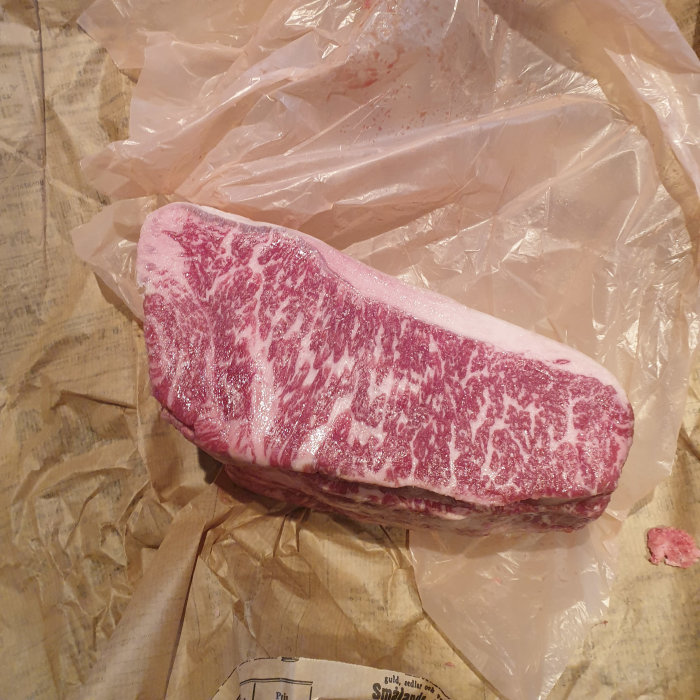 En bit Wagyu AA5-kött med marbling score 6/7+ på slaktarpapper.