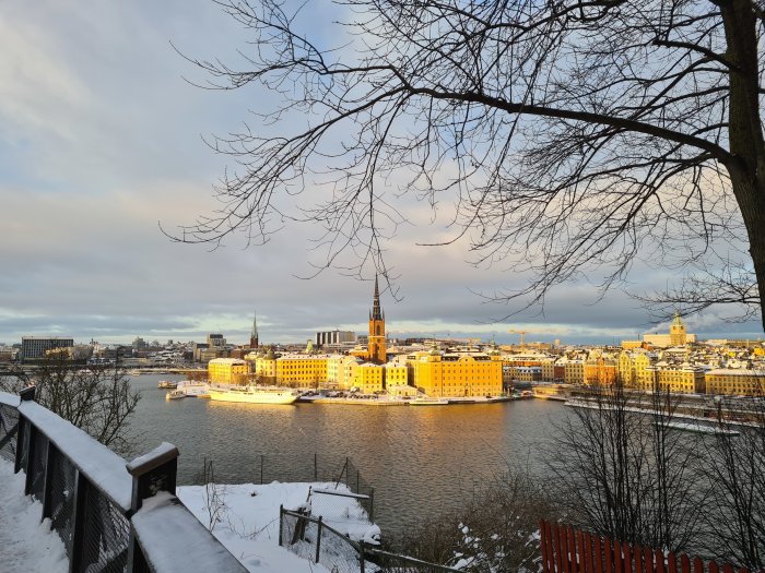 Utsikt över Riddarholmen och snötäckta byggnader i solnedgång från Monteliusvägen, Stockholm.