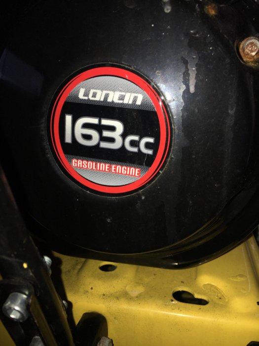 Etikett på svart motor som anger "Loncin 163cc Gasoline Engine" monterad på gul maskin.