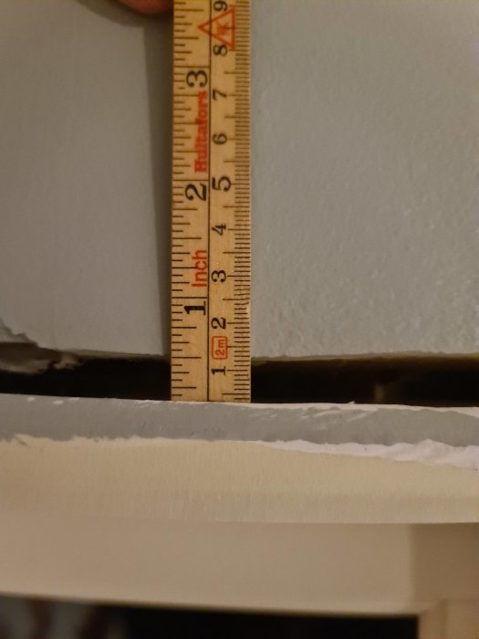 En tumstock mäter avståndet mellan fönstrets insida och fönsterfodret, visar trångt utrymme.