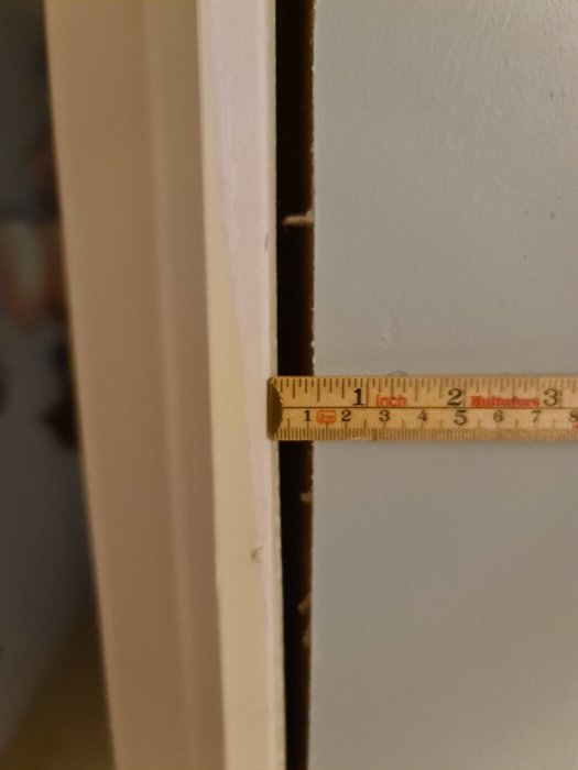 Närbild på ett fönstrets sidospalt med tumstock som visar avstånd för eventuell drevning.