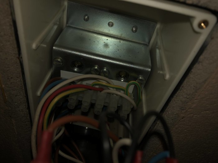 Interiör av styrpanel till vedspis med synliga värmekanaler och fläkt, kablar och anslutningar.