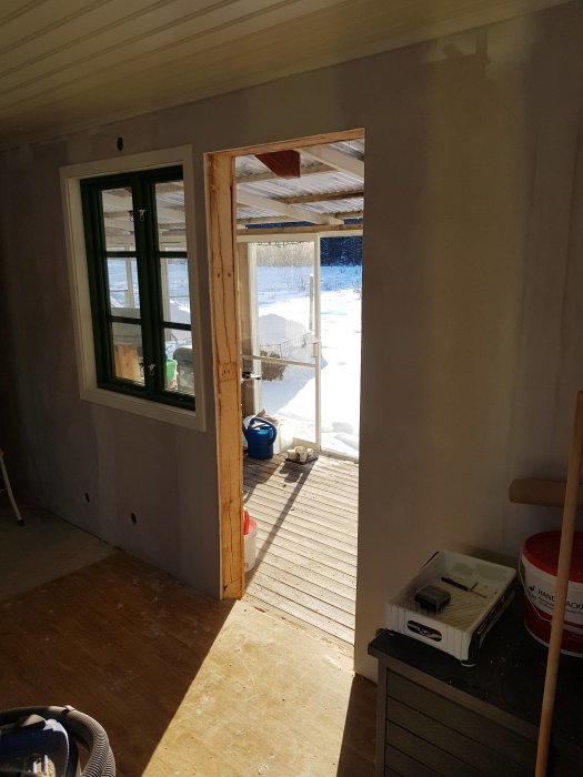 Altandörr och karm borttagna i ett rum under renovering, utsikt mot snöig altan.